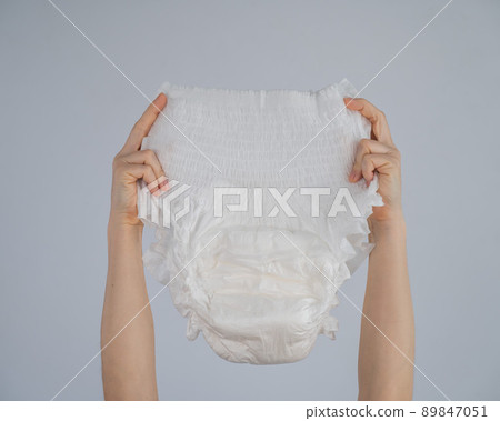 A woman holds an adult diaper on a white background. Incontinence problems. A woman holds an adult diaper on a white background. Incontinence problems. 89847051