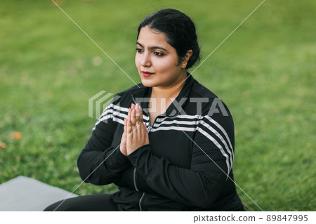 A young Indian woman meditates with her eyes closed in the open air A young Indian woman meditates with her eyes closed in the open air 89847995