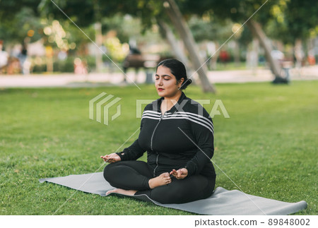 A young Indian woman meditates with her eyes closed in the open air. A young Indian woman meditates with her eyes closed in the open air. 89848002