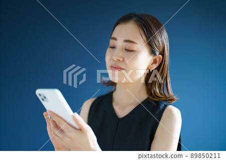A woman watching a screen of a smartphone A woman watching a screen of a smartphone 89850211