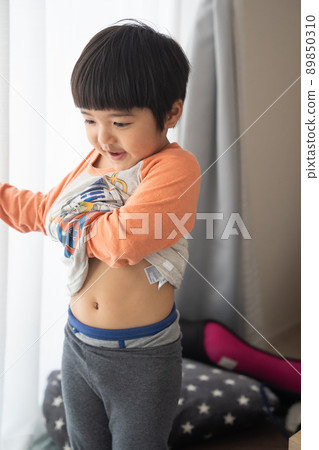 一個 4 歲的男孩在明亮的兒童房換衣服 89850310