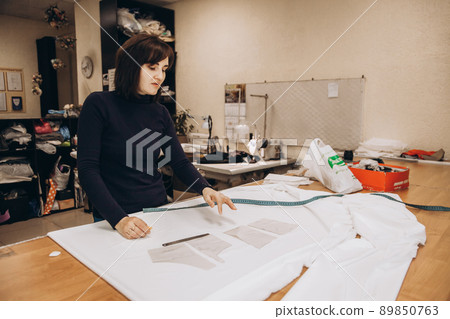 The tailor lays out the patterns on the fabric and begins to sew clothes The tailor lays out the patterns on the fabric and begins to sew clothes 89850763