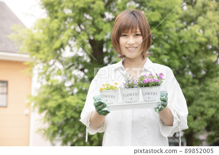 A smiling woman who grows flowers in a planter and enjoys gardening 89852005