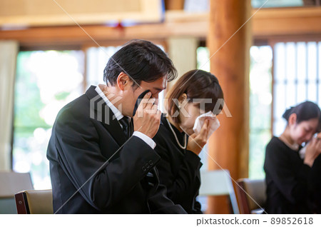 Bereaved family (couple) crying at the funeral 89852618