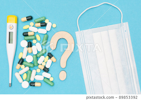 Wooden question mark, thermometer, medical mask and different drugs with pills on a blue background. Treatment choice concept. Flat lay. Top view. 89853392