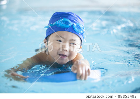 Boy swimming on a kickboard Boy swimming on a kickboard 89853492