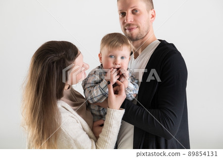 Young happy parents with their baby in the spotlight on white background 89854131