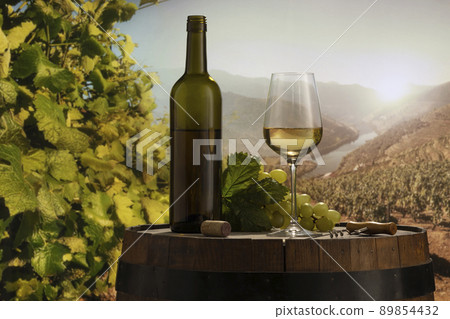 Design for card, magazine or brochure cover. White wine glass and bottle on wooden barrel over nature landscape background. Winemaking and festivals concept 89854432
