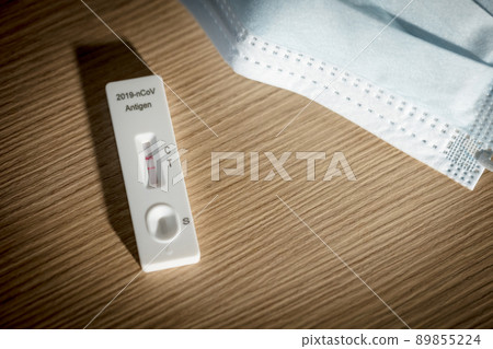 positive result of covid-19 self test kit with face mask on wood background 89855224