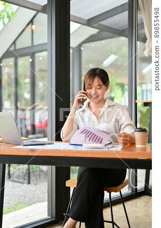 Asian millennial business consultant talking on the phone with business client Asian millennial business consultant talking on the phone with business client 89855498