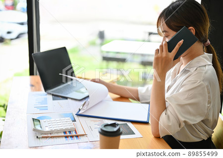 Female office worker talking on the phone, calling her business supplier. Female office worker talking on the phone, calling her business supplier. 89855499