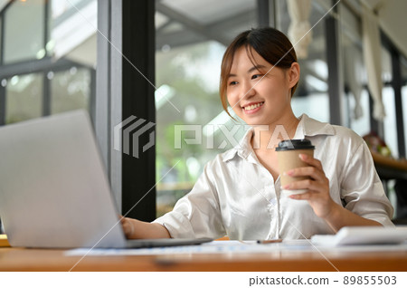 Female office worker or marketing staff using laptop computer and having a coffee 89855503