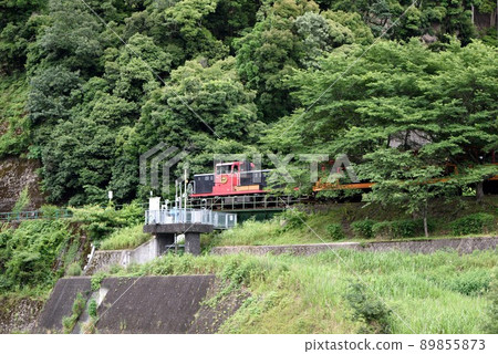 Kyoto: Early summer, fresh green Sagano trolley train, in front of Kameoka station 89855873