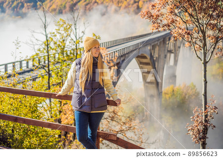 Montenegro. Woman touriste in background of Dzhurdzhevich Bridge Over The River Tara foggy morning. Travel around Montenegro concept. Sights of Montenegro 89856623