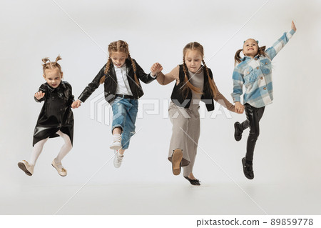 Happy school and preschool age children, beautiful girls jumping isolated on grey studio background. Beauty, kids fashion, education, happy childhood concept. Happy school and preschool age children, beautiful girls jumping isolated on grey studio background. Beauty, kids fashion, education, happy childhood concept. 89859778