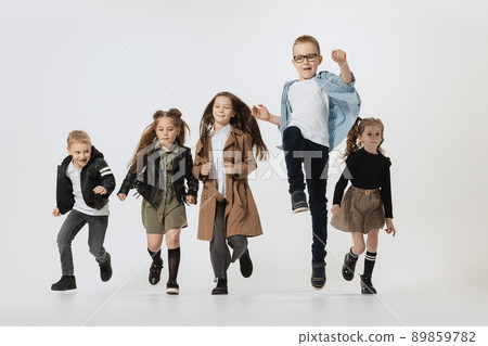 Happy school and preschool age children, girls and boys running, jumping isolated on grey studio background. Beauty, kids fashion, education, happy childhood concept. Happy school and preschool age children, girls and boys running, jumping isolated on grey studio background. Beauty, kids fashion, education, happy childhood concept. 89859782