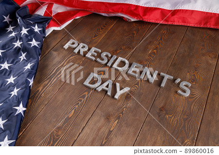 words presitdents day laid with silver letters on wooden surface near US flag words presitdents day laid with silver letters on wooden surface near US flag 89860016