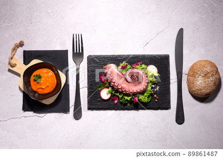 Stew octopus tentacle on stone plate on white background Top view. 89861487