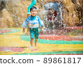 Asian boy play and run on the  spray water area with swimsuit 89861817