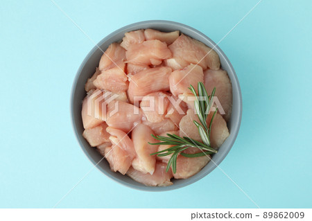 Pieces of raw chicken fillet in bowl on blue background Pieces of raw chicken fillet in bowl on blue background 89862009