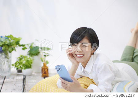 Young woman looking at her smartphone in the living room Young woman looking at her smartphone in the living room 89862237