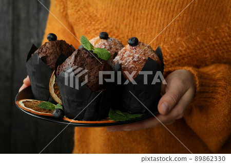 Woman in sweater holds plate with muffins, close up Woman in sweater holds plate with muffins, close up 89862330