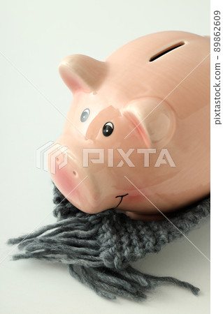 Piggy bank with knitted scarf on white background Piggy bank with knitted scarf on white background 89862609