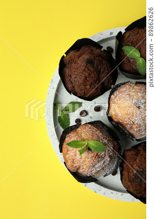 Tray with chocolate muffins on yellow background Tray with chocolate muffins on yellow background 89862626