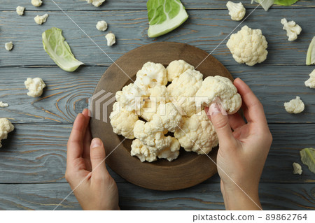Female hands take with bowl slice cauliflower on wooden background 89862764