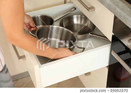 Woman pulls a saucepan out of the kitchen table 89862870