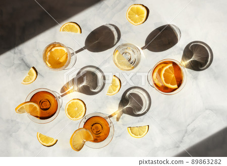 Summer cocktails in the sunlight. Fresh juicy beverages in glasses with shadows making trendy pattern. Delicious lemonade, cold tea, soda and water on gray marble background Summer cocktails in the sunlight. Fresh juicy beverages in glasses with shadows making trendy pattern. Delicious lemonade, cold tea, soda and water on gray marble background 89863282