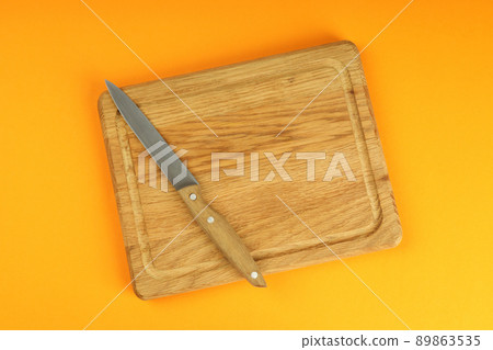Cutting board with knife on orange background 89863535