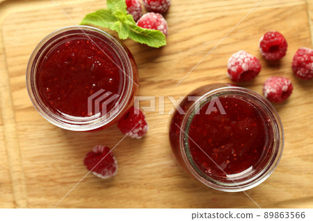 Glass jars of raspberry jam with ingredients on wooden board Glass jars of raspberry jam with ingredients on wooden board 89863566