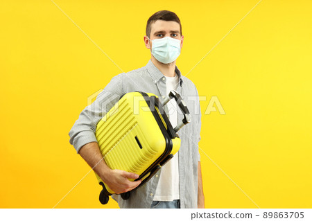 Traveling concept during coronavirus with young man on yellow background Traveling concept during coronavirus with young man on yellow background 89863705