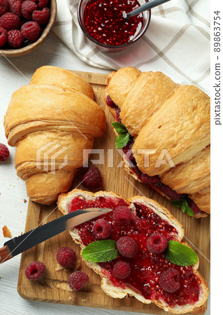 Concept of delicious food with croissants with raspberry jam on white wooden background Concept of delicious food with croissants with raspberry jam on white wooden background 89863754
