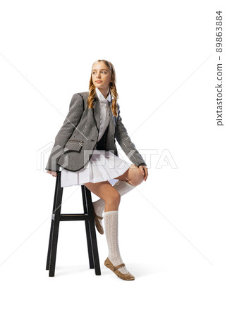 Portrait of stylish teen girl in skirt and jacket posing on chair isolated over white studio background Portrait of stylish teen girl in skirt and jacket posing on chair isolated over white studio background 89863884