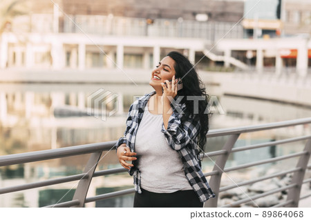 An Indian girl walks along the embankment and talks on the phone. An Indian girl walks along the embankment and talks on the phone. 89864068
