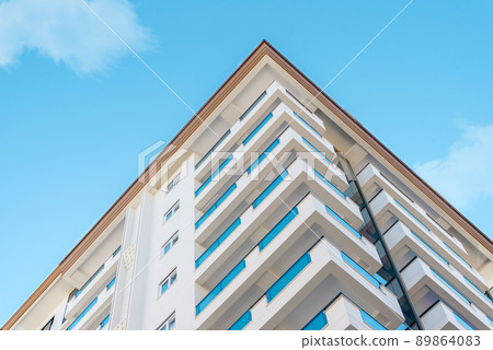 Corner of a residential apartment building against the blue sky. Corner of a residential apartment building against the blue sky. 89864083