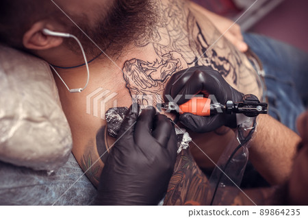Professional tattoo artist focused on his work in tattoo studio Professional tattoo artist focused on his work in tattoo studio 89864235