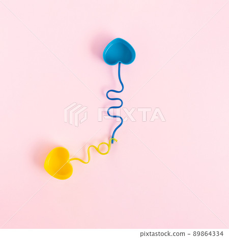 Pastel colored plastic dishes and drinking straws placed like clock hands on a pink background. Pastel colored plastic dishes and drinking straws placed like clock hands on a pink background. 89864334