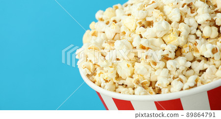 Paper cup with popcorn on blue background Paper cup with popcorn on blue background 89864791
