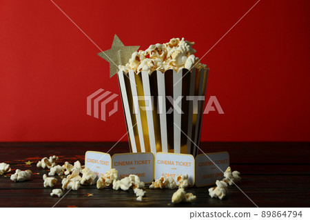 Paper box with popcorn, and tickets against red background Paper box with popcorn, and tickets against red background 89864794
