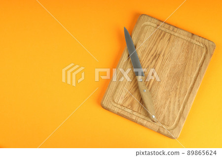 Cutting board with knife on orange background Cutting board with knife on orange background 89865624