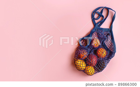 Net bag with fruit on bright background. Zero waste and ecology conservation concept. Fresh apples, tangerines, avocado and pomegranate in a reusable eco friendly shopping bag Net bag with fruit on bright background. Zero waste and ecology conservation concept. Fresh apples, tangerines, avocado and pomegranate in a reusable eco friendly shopping bag 89866300
