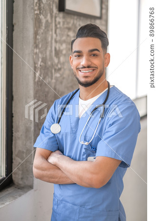 Joyous physician posing for the camera in his office Joyous physician posing for the camera in his office 89866768