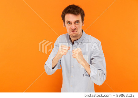 Man ready to fight. Boxing pose. Studio shot, orange background Man ready to fight. Boxing pose. Studio shot, orange background 89868122