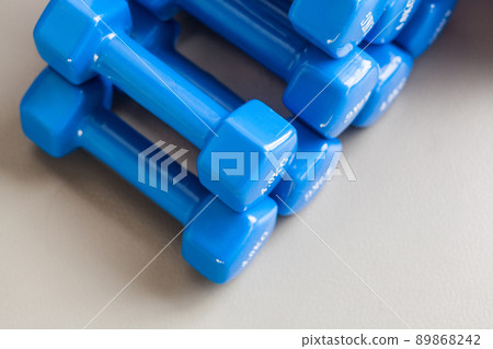 Many blue dumbbells folded on the gray floor. Studio shot Many blue dumbbells folded on the gray floor. Studio shot 89868242