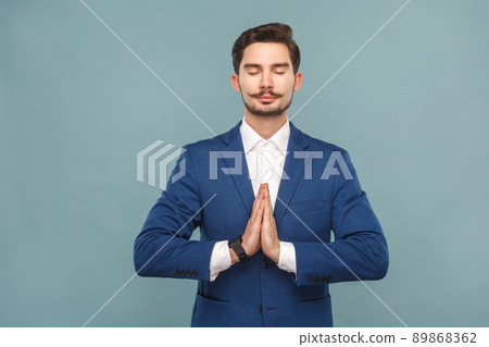 Relaxation and harmony. Man meditating after work. Business people concept, richly and success. Indoor, studio shot on light blue background Relaxation and harmony. Man meditating after work. Business people concept, richly and success. Indoor, studio shot on light blue background 89868362