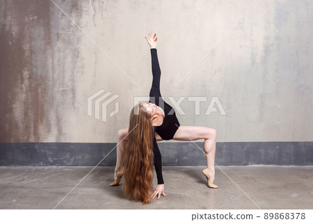 Beautiful young adult long haired woman dancing in studio. Indoor shot, gray wall Beautiful young adult long haired woman dancing in studio. Indoor shot, gray wall 89868378