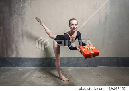 Beautiful ballerina balance in one leg and holding red gift box. Indoor 89868462